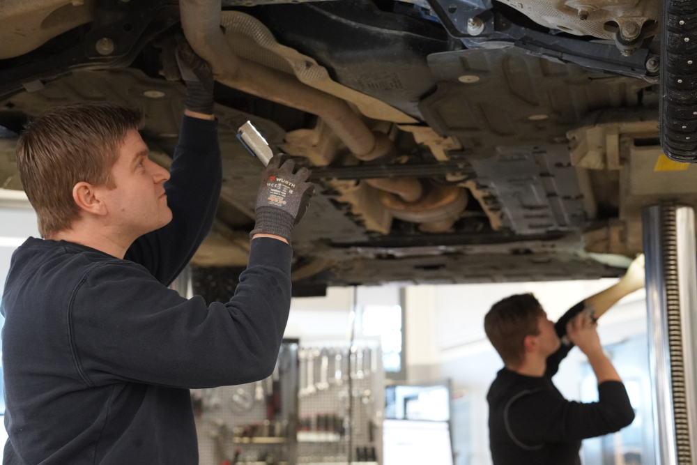 To mekanikere skrur på understellet til en bil