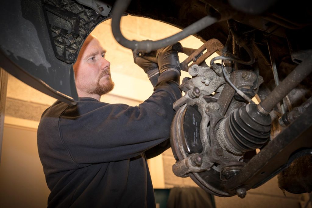 Bilmekaniker jobber på bil i verksted