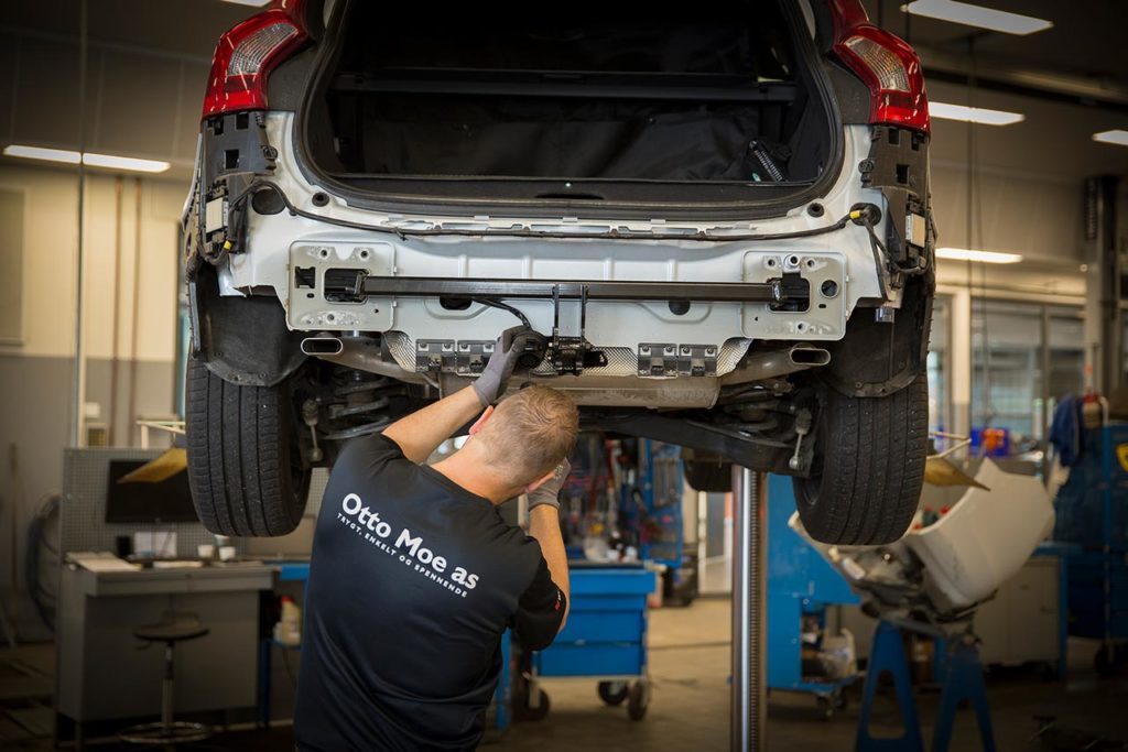 Mann skrur på en bil i et bilverksted
