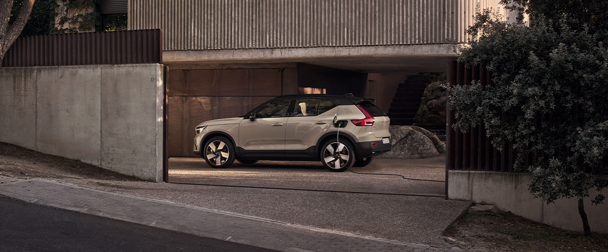 En sandfarget Volvo EX40 sett fra siden i en betonggarasje