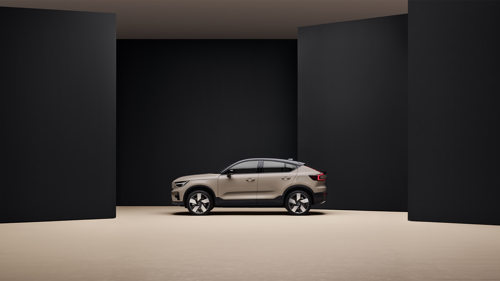 En sandfarget Volvo EX40 sett direkte fra siden